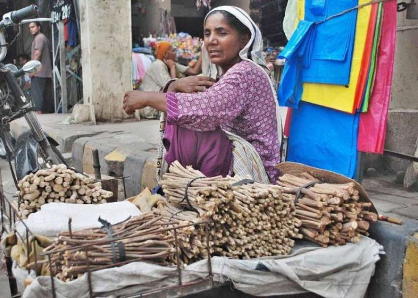 لاہور: ایک خاتون مسواکیں فروخت کرنے کے لیے فٹ پاتھ پر بیٹھے ..
