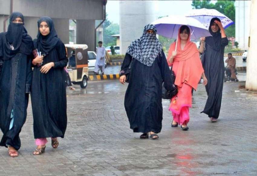 راولپنڈی: بارش کے دوران خواتین بارش سے بچنے کے لیے چھتری ..