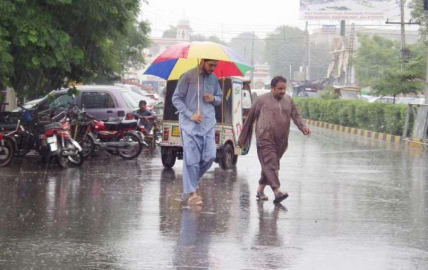 فیصل آباد: موسلا دھار باش کے دوران ایک شہری چھتری تانے اپنی ..
