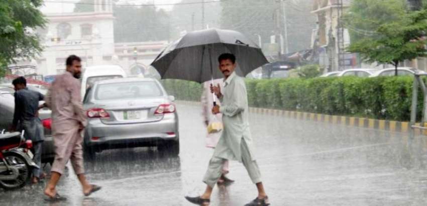 فیصل آباد: موسلا دھار باش کے دوران ایک شہری چھتری تانے اپنی ..