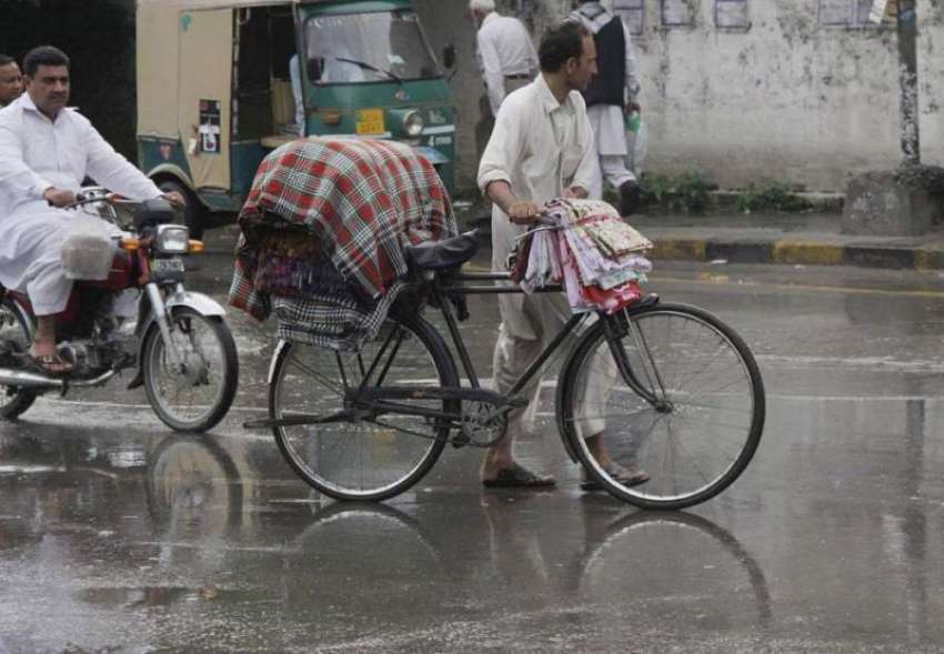 لاہور: ایک شخص کپڑے فروخت کرنے کے لیے سائیکل پر رکھے جا رہا ..