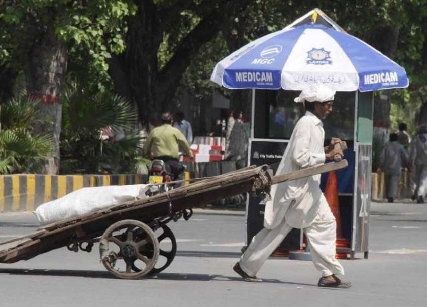 لاہور: محنت کش ہتھ ریڑھی پر سامان رکھے مال روڈ سے گزر رہا ..