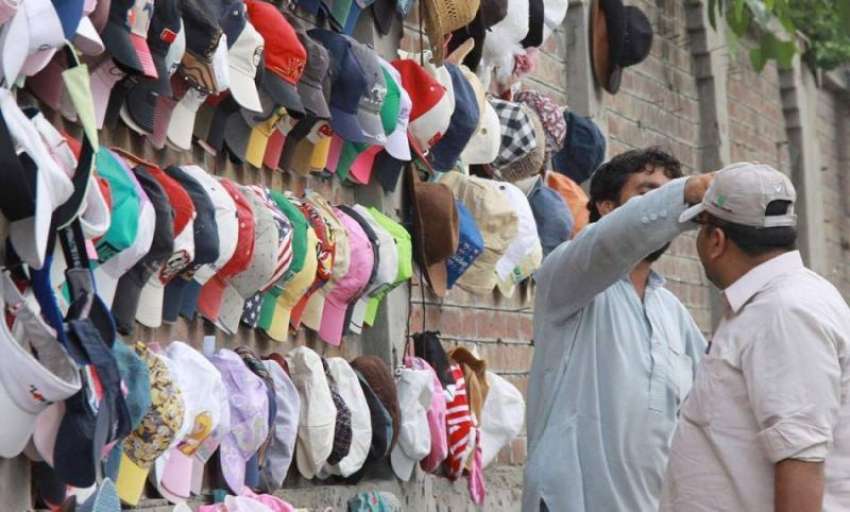 لاہور: ایک شخص دھوپ سے بچنے کے لیے ٹوپی خرید رہا ہے۔