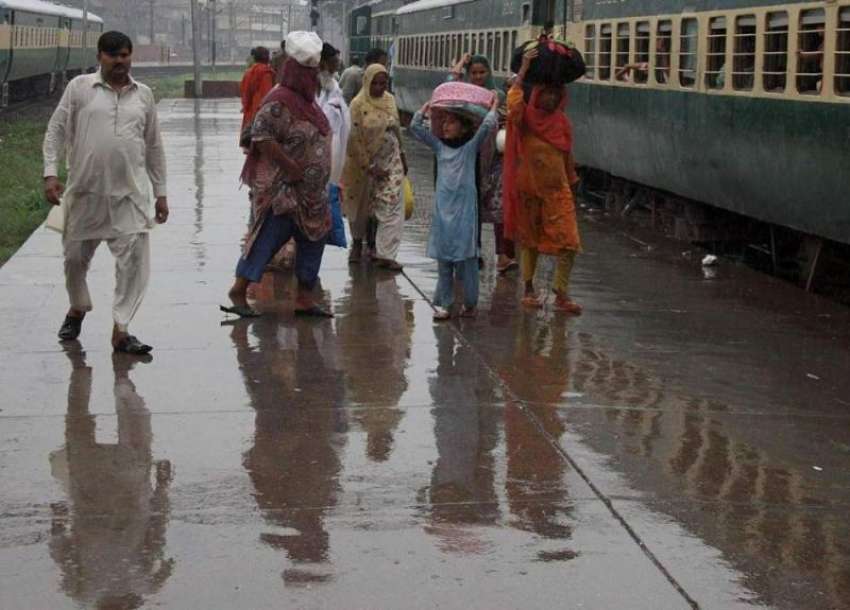لاہور: شہر میں ہونیوالی بارش کے دوران ریلوے اسٹیشن پر مسافر ..
