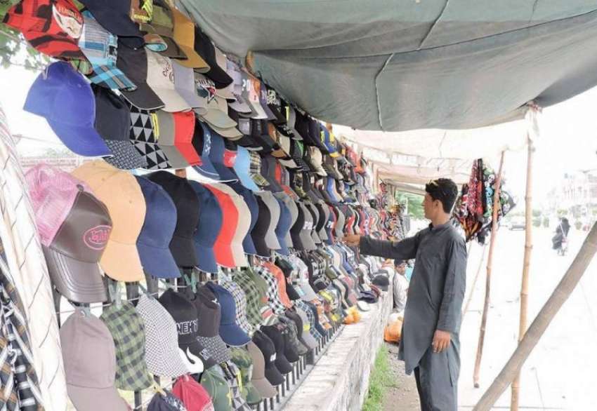 لاہور: ملتان روڈ پر ایک شخص ٹوپیاں فروخت کرنے کے لیے جنگلے ..