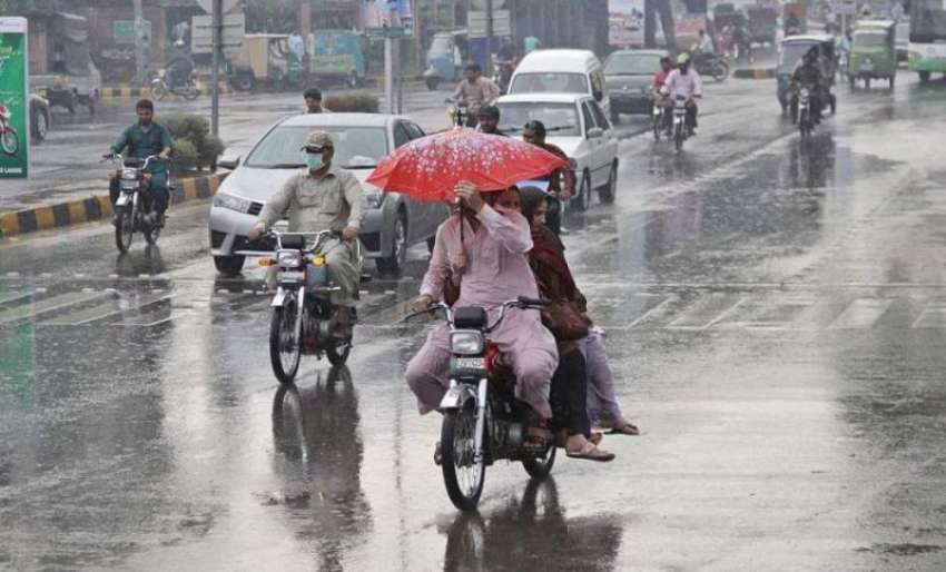 لاہور: شہر میں ہونیوالی بارش کے دو ران ایک موٹرسائیکل سوار ..