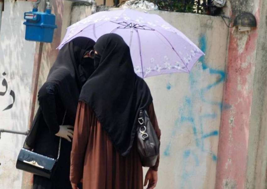 پشاور: دھوپ سے بچنے کے لیے طالبات چھتری تانے وین کا انتظار ..