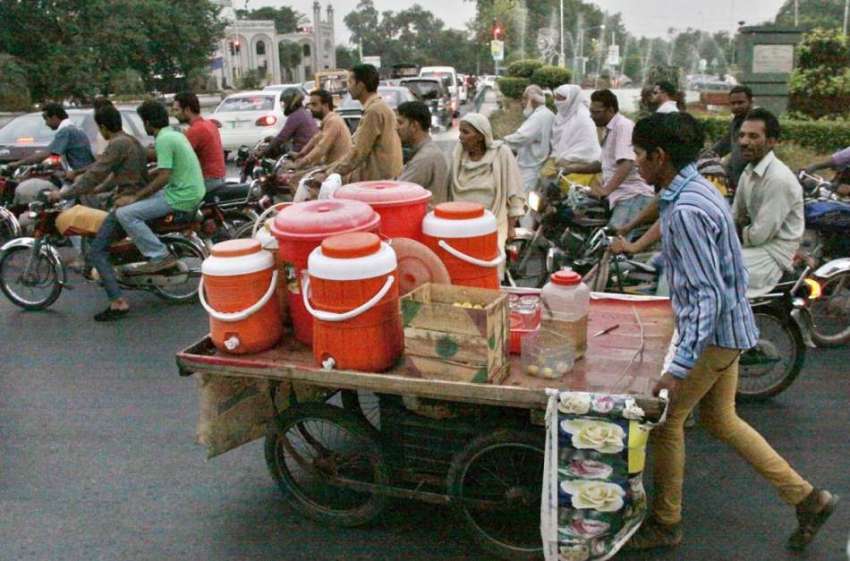 لاہور: ایک محنت کش ٹھنڈا مشروب بیچنے کے لیے ہتھ ریڑھ لیے ..