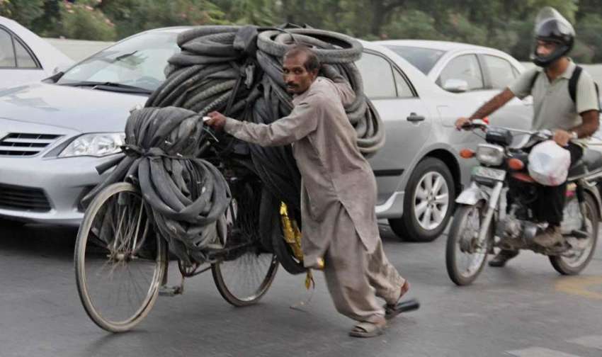 لاہور: ایک شخص سائیکل پر پرانے ٹائرز اور ٹیوبز رکھے جا رہا ..