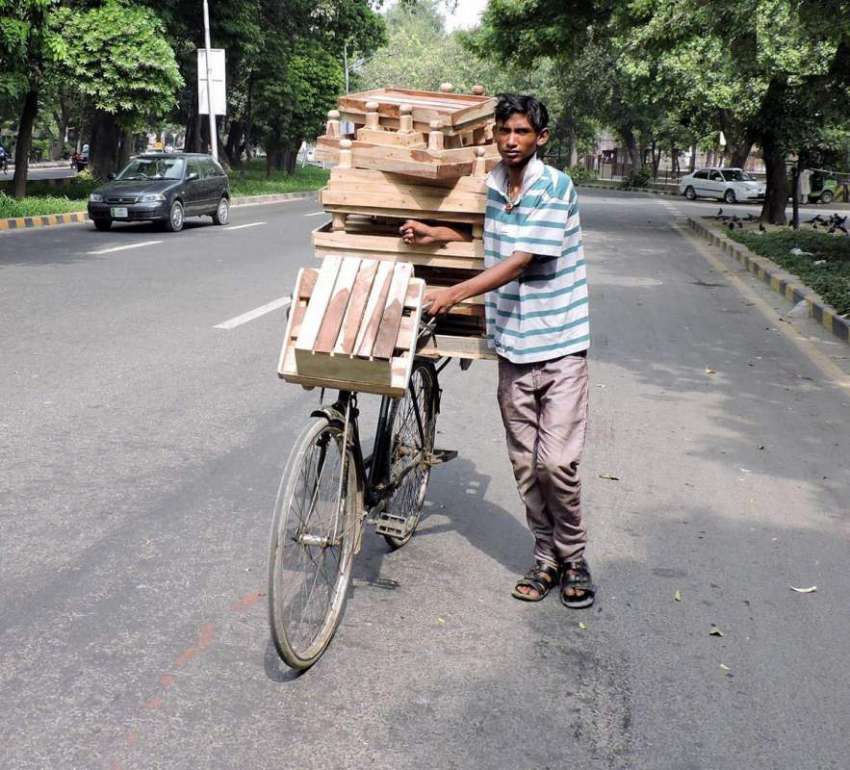 لاہور: ایک محنت کش سائیکل پر فریج رکھنے والے لکڑی کے سٹینڈ ..