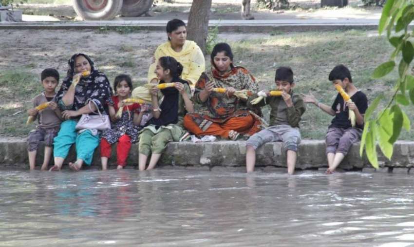 لاہور: خواتین اور بچے نہر کنارے بیٹھے چھلیاں کھا رہے ہیں۔