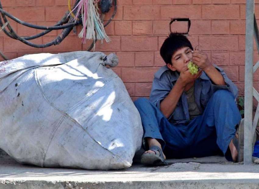راولپنڈی: ایک خانہ بدوش بچہ سائے میں بیٹھا انگور کھا رہا ..