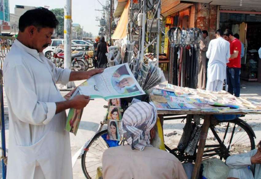 راولپنڈی: سڑک کنارے لگائے گئے اخبار کے سٹال پر ایک شخص مطالعہ ..