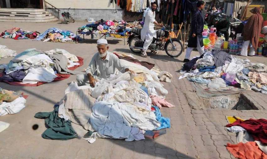 راولپنڈی: ہفتہ وار جمعہ بازار میں ایک محنت کش کار آمد کپڑے ..