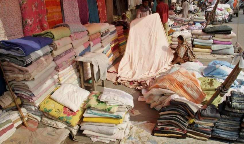 لاہور: ایک شخص نے سردیوں کے پیش نظر لنڈا بازار میں گرم چادروں ..