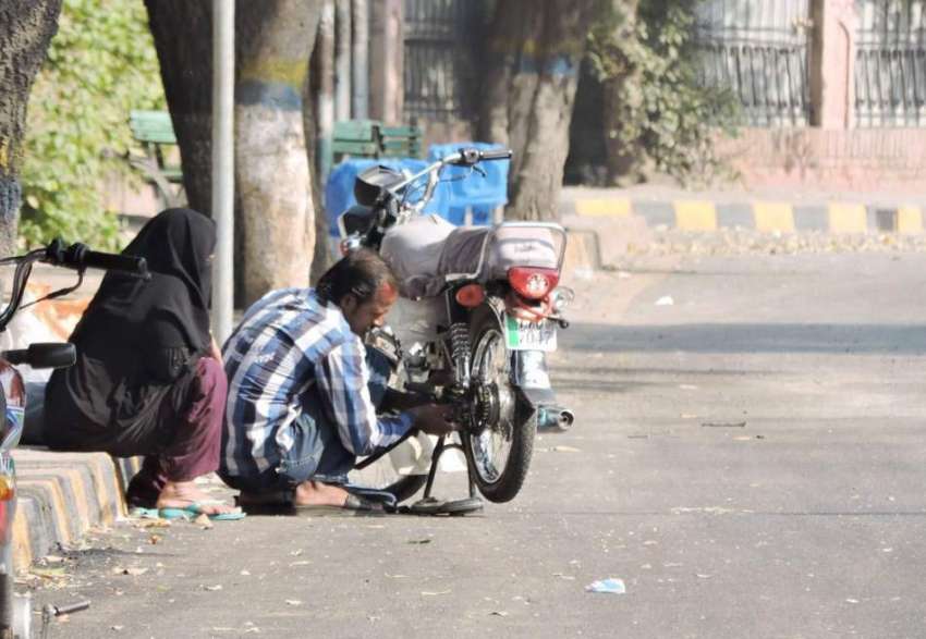 لاہور: ایک شخص مال روڈ پر فٹ پاتھ پر عارضی دکان لگائے موٹر ..