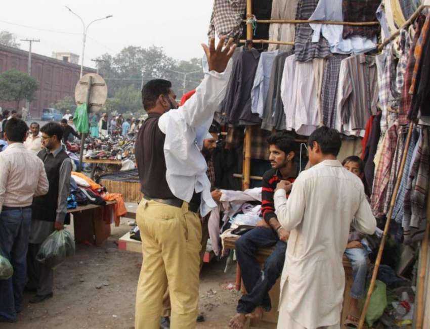 لاہور: ایک پولیس اہلکار لنڈا بازار سے کپڑے خرید رہا ہے۔