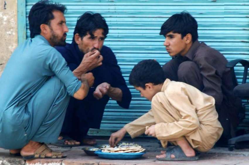 راولپنڈی: محنت کش روڈ کنارے کھانا کھا رہے ہیں۔