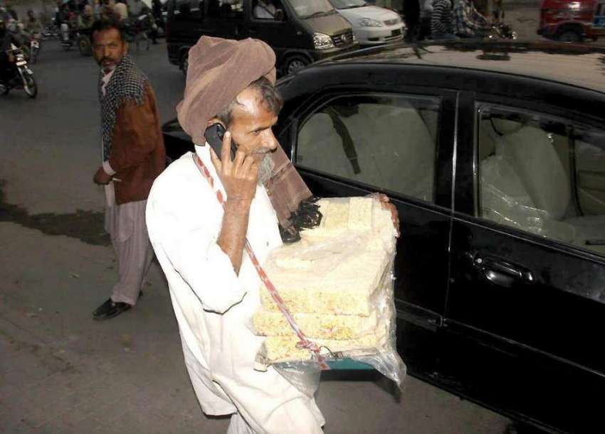 لاہور: ایک معمر محنت کش فون سنتے ہوئے جا رہا ہے۔
