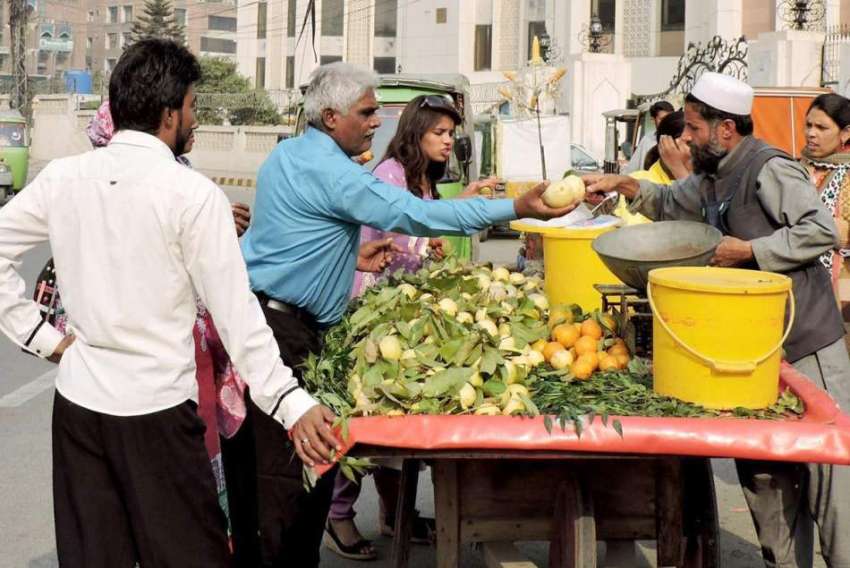 لاہور: ایوان اقابل کے سامنے شہری ریڑھی سے امرود خرید رہے ..