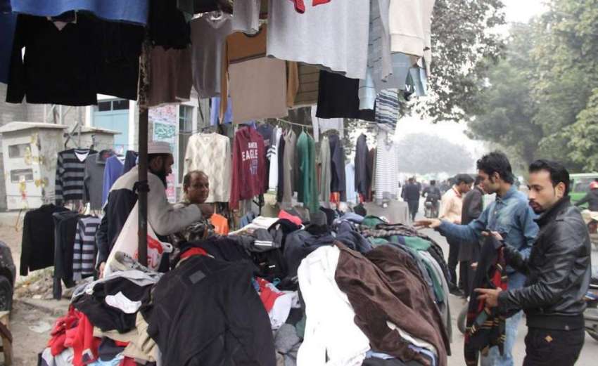لاہور: شہری سڑک کنارے ریڑھی سے گرم کپڑے خرید رہے ہیں۔