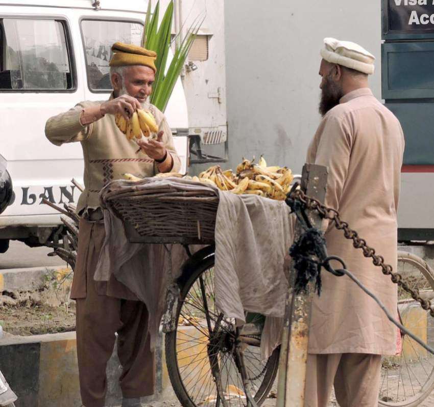 لاہور: ایک شہری پھل فروش سے کیلے خرید رہا ہے۔