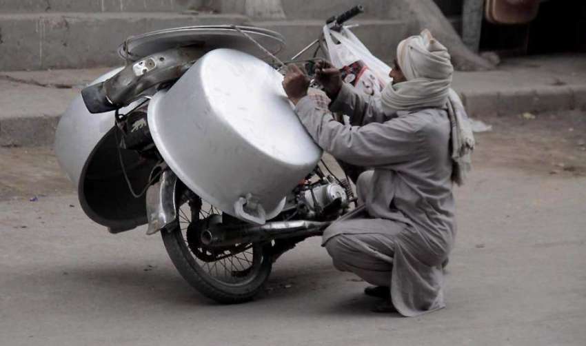 لاہور: ایک شخص بازار سے خریدے گئے برتن موٹر سائیکل کے پیچھے ..