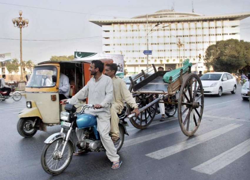 لاہور: دو شہری موٹر سائیکل پر ریڑھا کھینچ کر لیجا رہے ہیں، ..