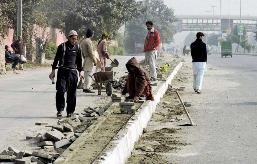 لاہور: جیل روڈ پر مزدور فٹ پاتھ تعمیر کر رہے ہیں۔