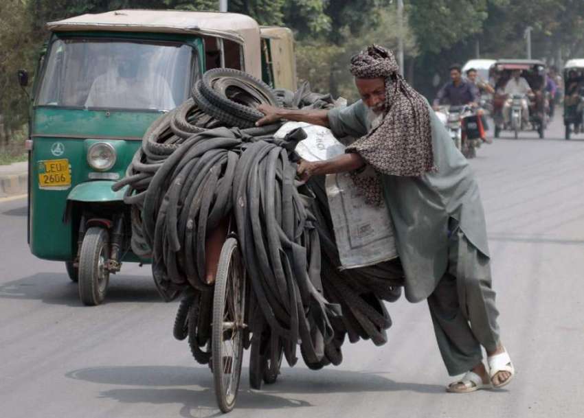 لاہور: ایک محنت کش سائیکل پر پرانے ٹائر اور ٹیوبز لے کر جا ..