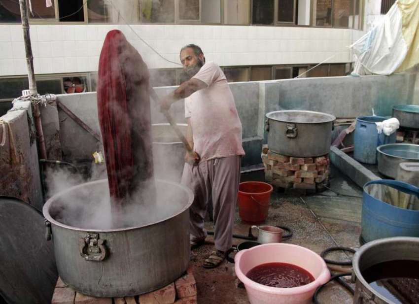 لاہور: شاہ عالم مارکیٹ میں ایک شخص کپڑوں کو رنگ کرنے میں ..
