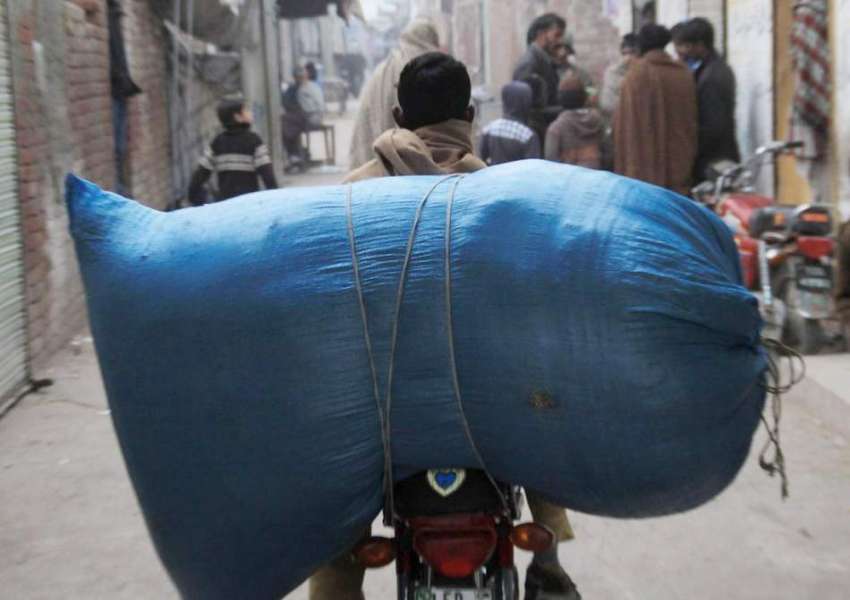 لاہور: ایک شہری موٹر سائیکل ک پیتھے بھاری سامان رکھے جا رہا ..