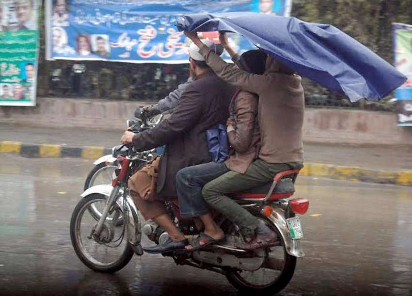 لاہور: شہر میں ہونیوالی بارش کے دوران موٹر سائیکل سوار شہری ..