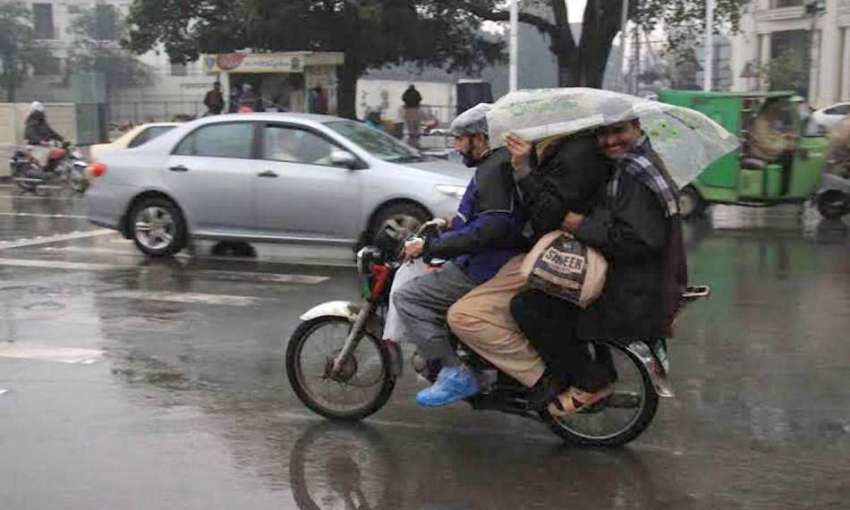 لاہور: موٹر سائیکل سوار بارش سے بچنے کے لیے سروں پر پلاسٹک ..