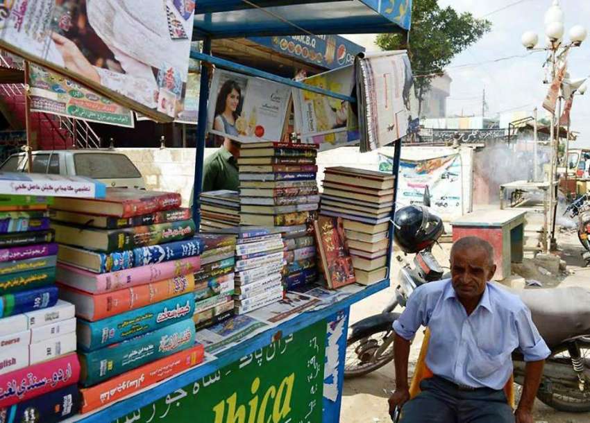 کراچی: ایک معمر شخص اپنے ٹھیلے پر کتابیں سجائے گاہکوں کا ..