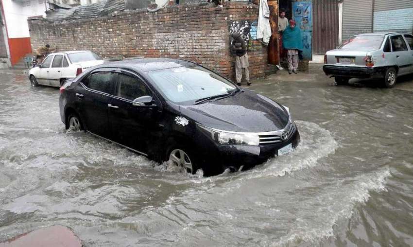 راولپنڈی:تیز بارش کے بعد جمع شدہ پانی سے ایک گاڑی گزر رہی ..