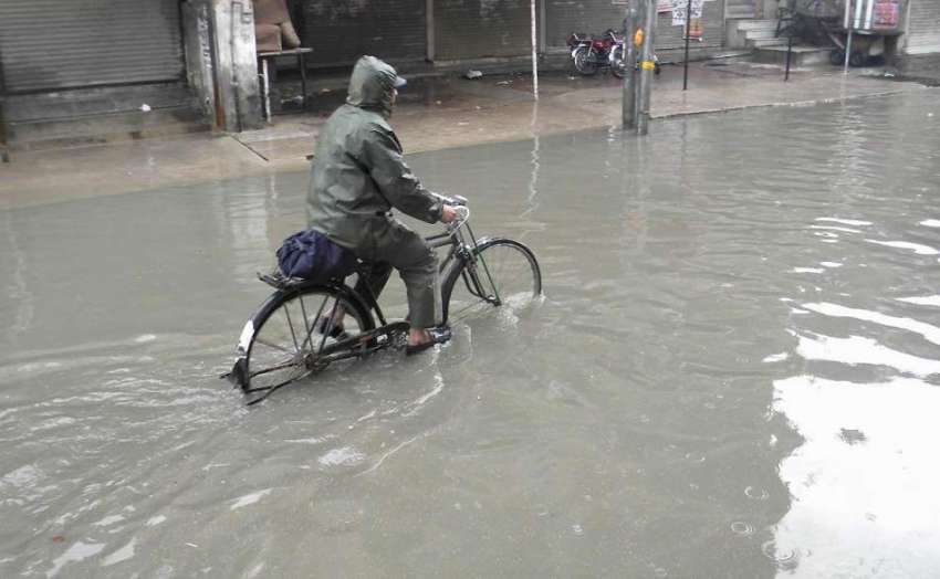 راولپنڈی: ایک سائیکل سوار بارش کے جمع شدہ پانی سے گزر رہا ..