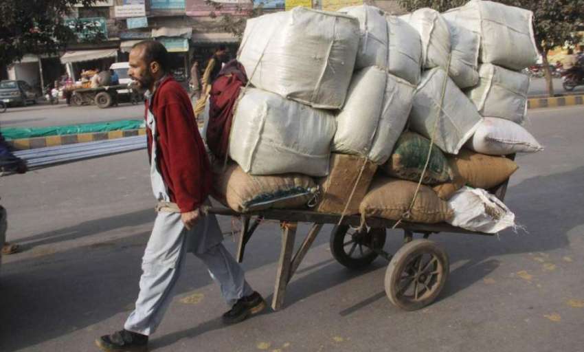لاہور: ایک محنت کش ہتھ ریڑھی پر بھاری سامان رکھے جا رہا ہے۔