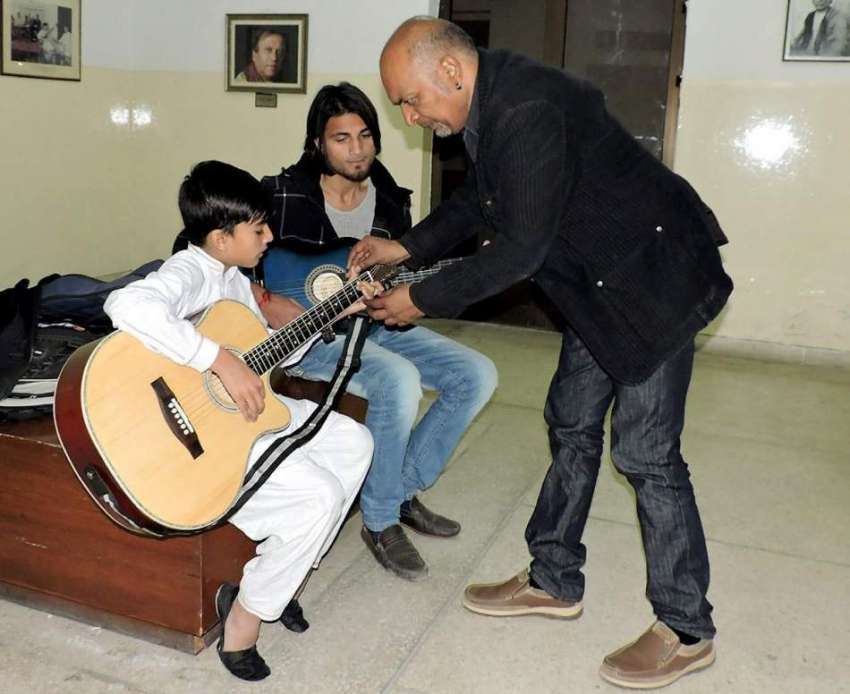 لاہور: صفدارتی ایواڈ یافتہ سجاد طافو ایک بچے کو گٹار بجانا ..