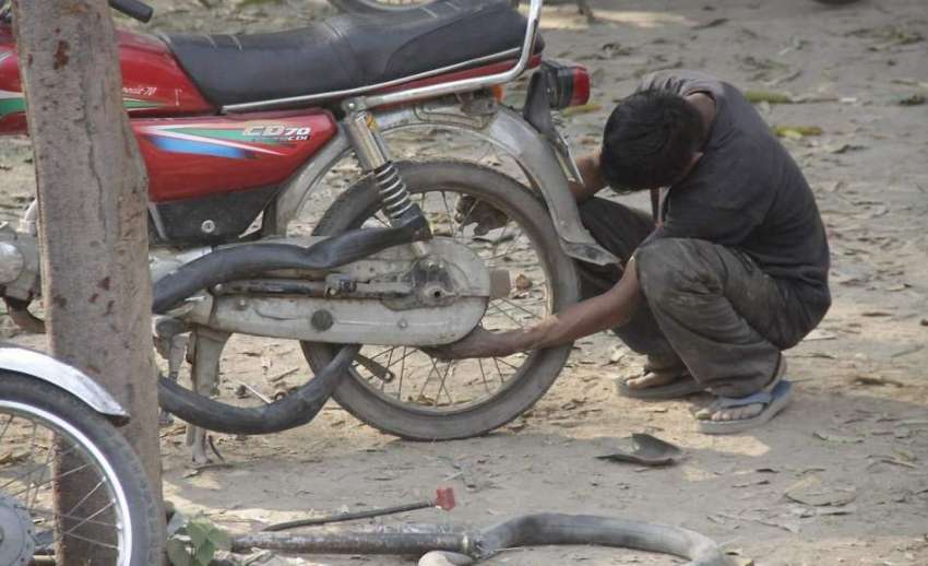 لاہور: ایک محنت کش سڑک کے کنارے موٹر سائیکل کے ٹائر کو پنکچر ..
