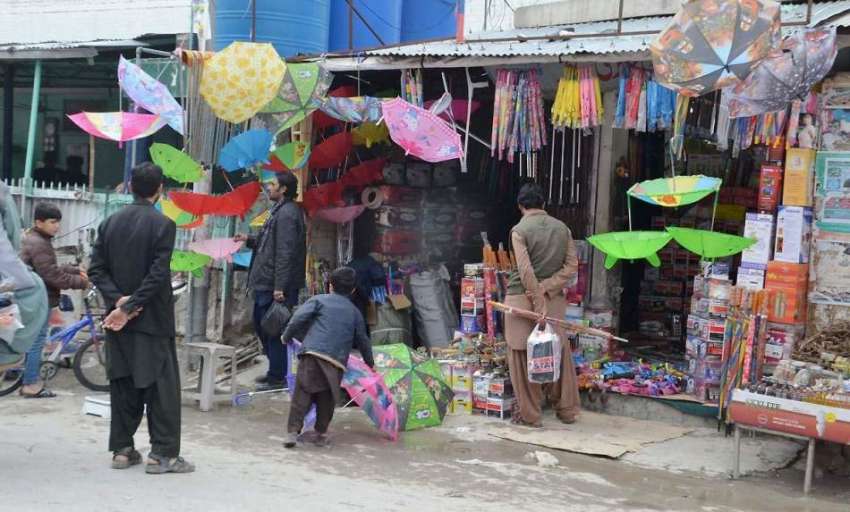 کوئٹہ: لیاقت بازار میں لوگ بارش سے بچنے کے لیے ایک دوکان ..