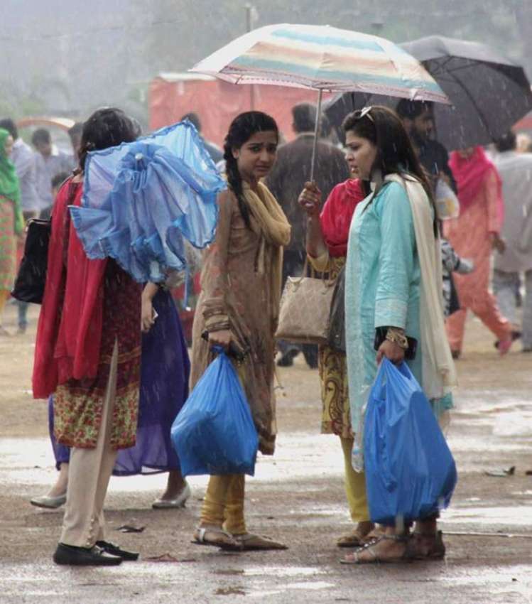 لاہور: جیلانی پارک میں دو خواتین نے بارش سے بچنے کے لیے چھتری ..