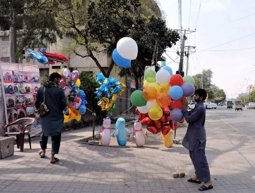 لاہور: لبرٹی چوک میں ایک شخص روڈ کنارے غبارے فروخت کر رہا ..