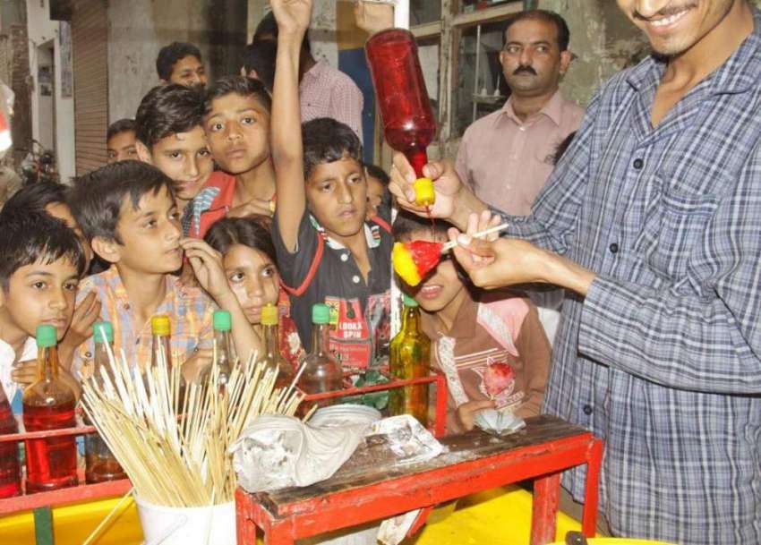 لاہور: گرمی کی شدت کم کرنے کے لیے بچے برف کے گولے خرید رہے ..