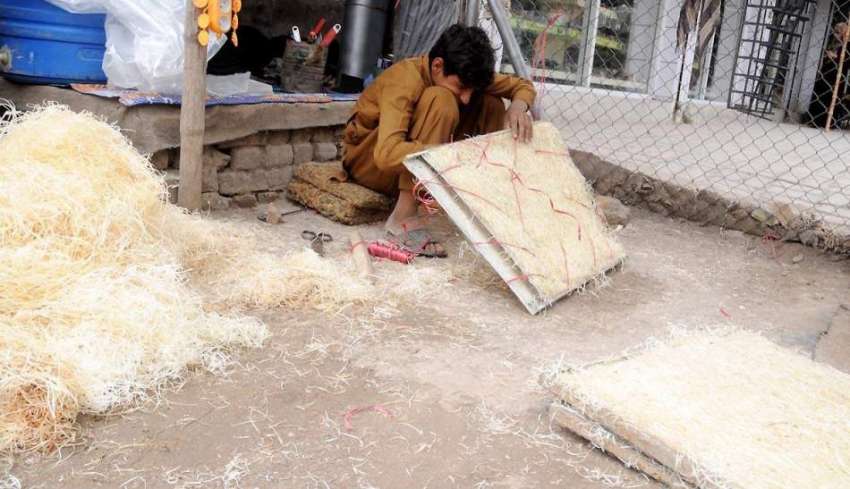 راولپنڈی: ایک محنت کش ایئر کولر کے لیے خسیں تیار کر رہا ہے۔