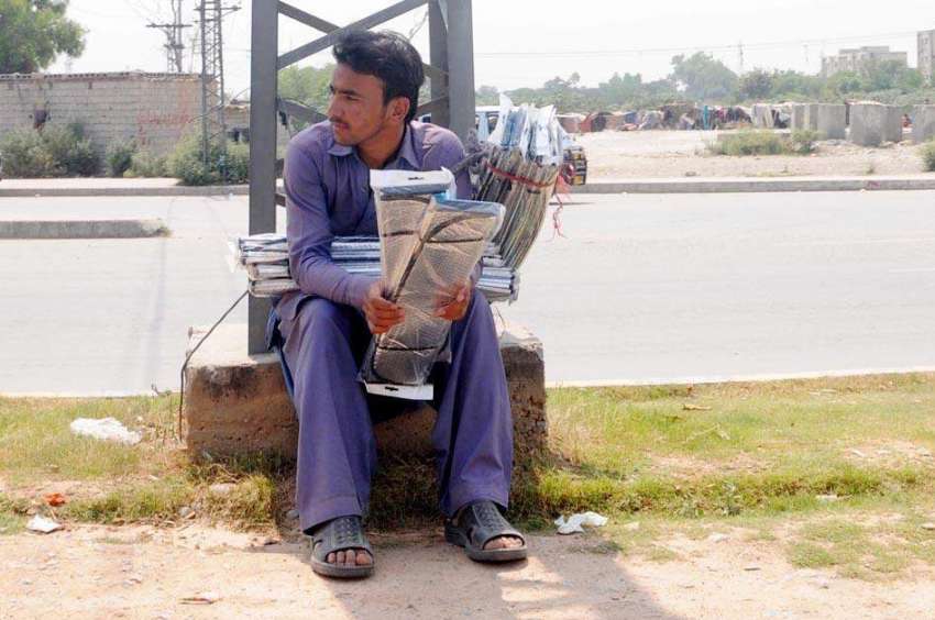 راولپنڈی: ایک محنت کش سڑک کنارے بیٹھا گاڑیوں کے لیے سن بلاکر ..