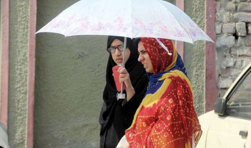 راولپنڈی: دھوپ سے بچنے کے لیے خواتین چھتری تانے جا رہی ہیں۔