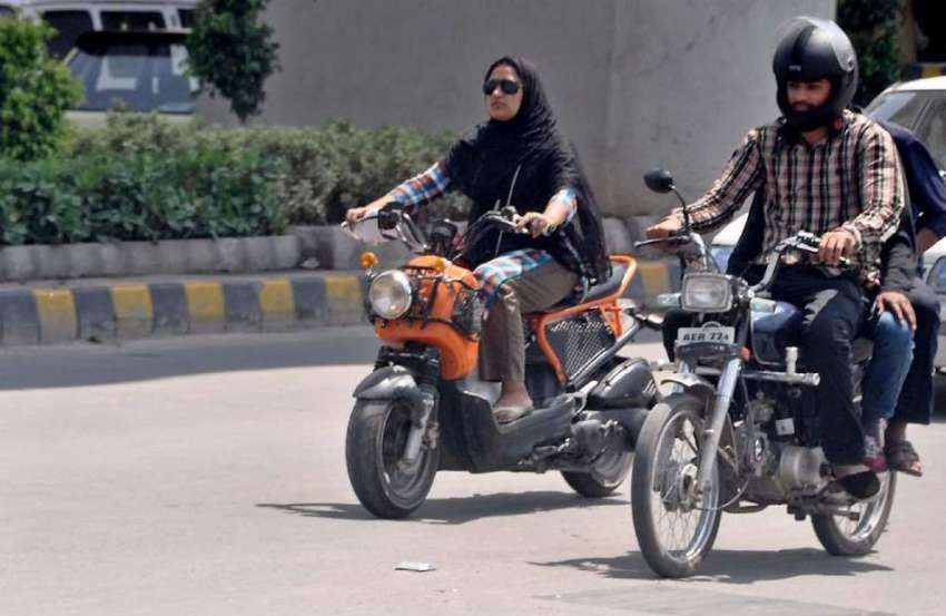 راولپنڈی: ایک خاتون سکوٹی چلاتے ہوئے مری روڈ سے گزر رہی ہے۔