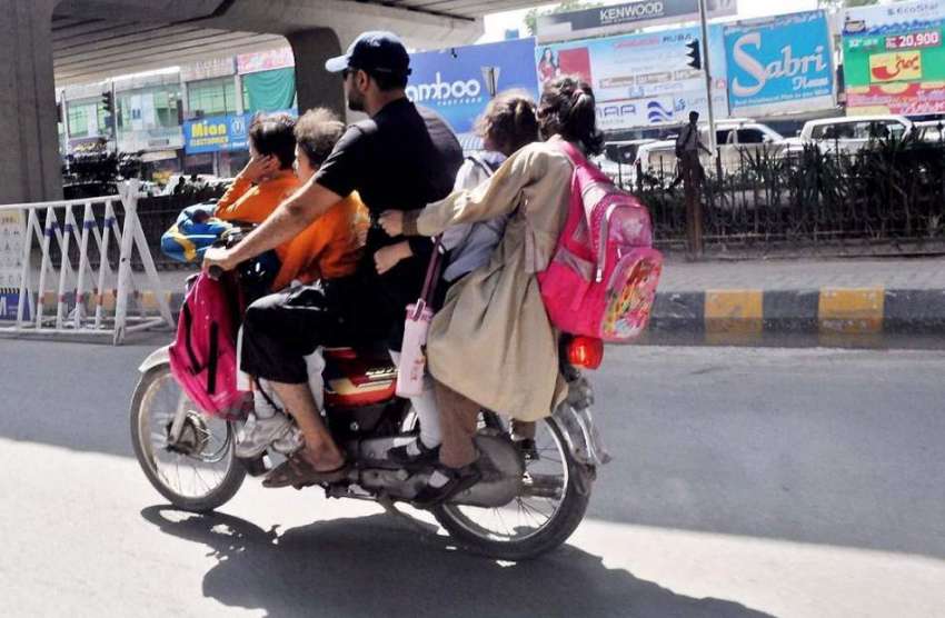 راولپنڈی: ایک موٹر سائیکل سوار اپنے بچوں کو بٹھائے مری روڈ ..