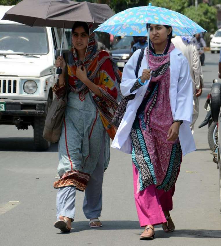 لاہور: دھوپ سے بچنے کے لیے خواتین چھتری لیے فیروزپور روڈ ..